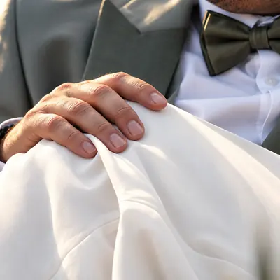 La main du marié sur la robe, nœud papillon vert